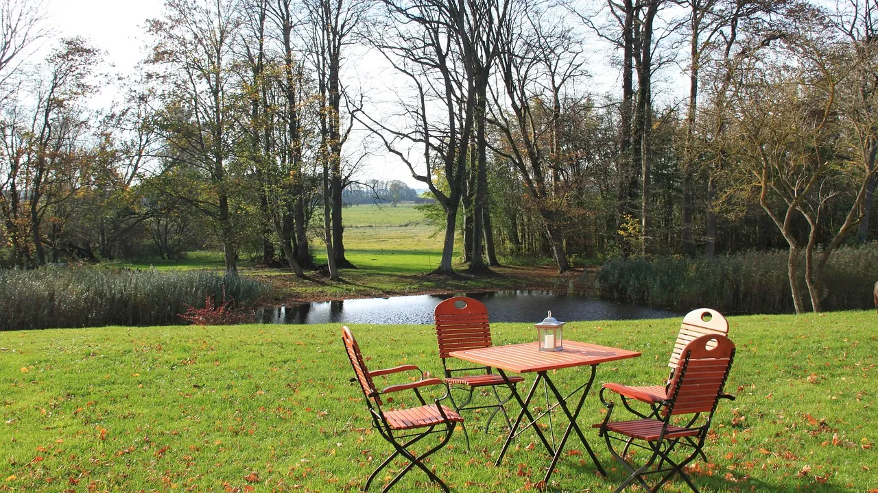 Quatre chaises de jardin autour d’une table, au bord d’un étang