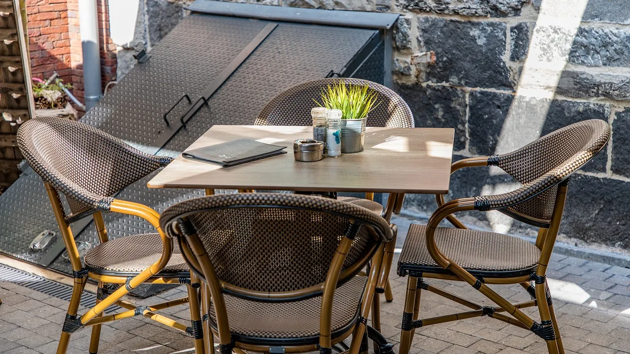 Une table de terrasse dressée, quatre fauteuils tournés vers le centre